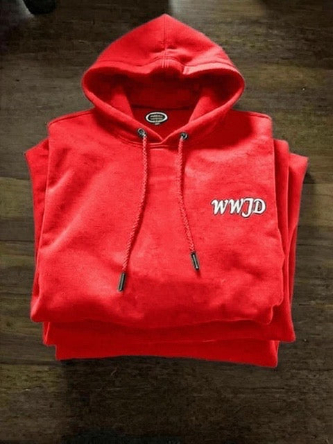 Folded red hoodie with 'WWJD' text on a wooden surface
